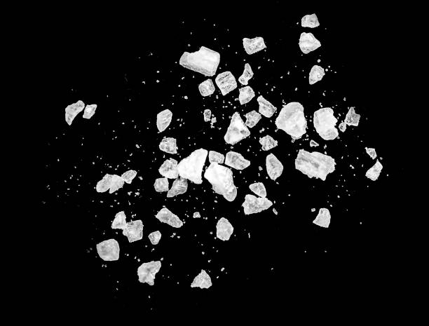 makroaufnahme von fallenden und fliegenden salzkristallen, die auf schwarz isoliert sind - salz mineral stock-fotos und bilder