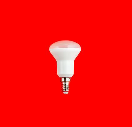 energy saving concept. led lamp isolated on red background