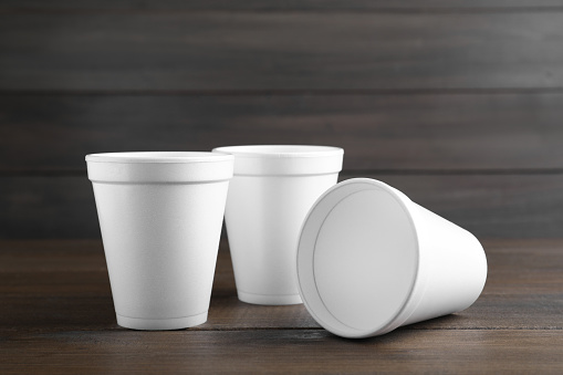 Three white styrofoam cups on wooden table