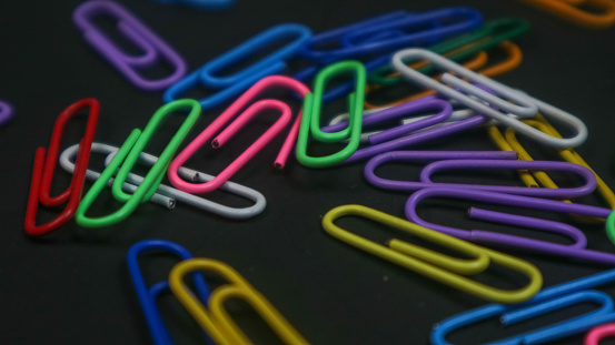 Colorful paper clips isolated on black background