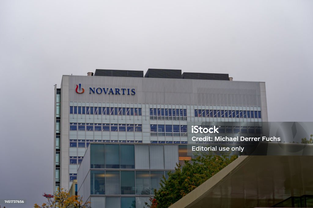 Novartis campus with facade of office building. Close-up of office tower with logo of Swiss pharmaceutical company Novartis at City of Basel on a gray autumn morning. Photo taken October 3rd, 2022, Basel, Switzerland. Architecture Stock Photo