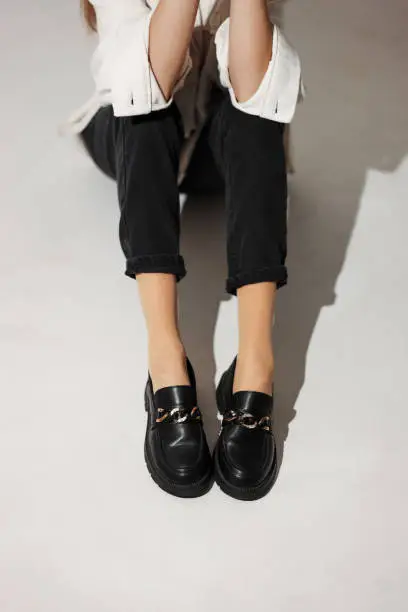 Photo of black loafers on female legs close-up