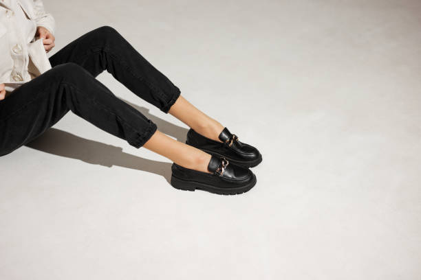 schwarze loafer an weiblichen beinen nahaufnahme - frau schuhe stock-fotos und bilder