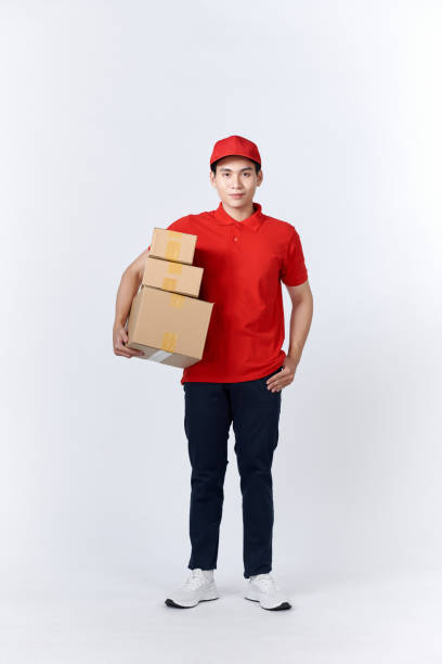 istock Delivery man in red uniform isolated on white background, studio portrait. 1451744519
