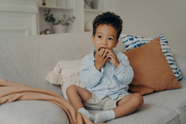 istock Hungry cute afro american boy eating cupcake while spending time at home 1451748343