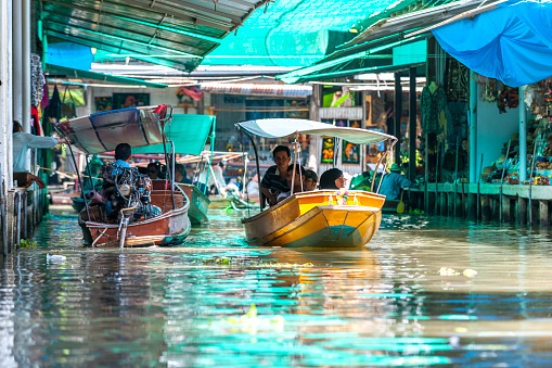 market vendors at the Damnoen Saduak floating market. The Damnoen Saduak floating market is a well-known travel destination for tourists visiting Thailand.