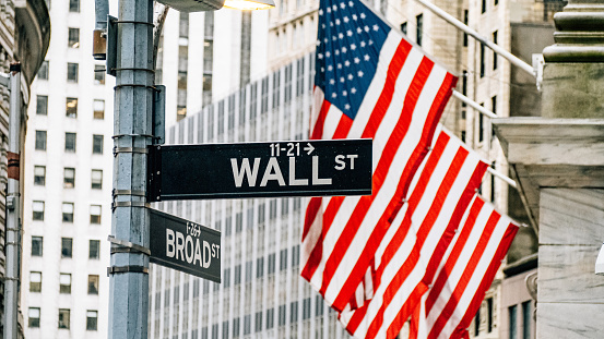 Wall street district in New York City with USA flags in the background. Famous financial district in New York City Lower Manhattan.