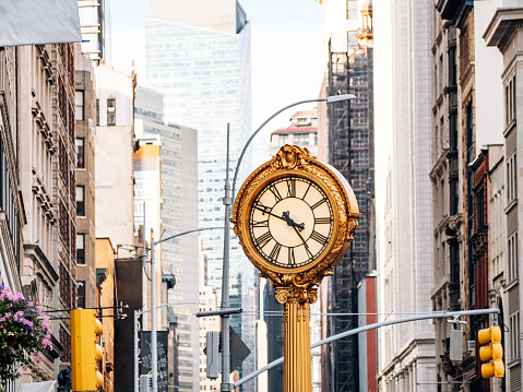 Young asian businesswoman using rope to pulling a clock with skyscrapers background