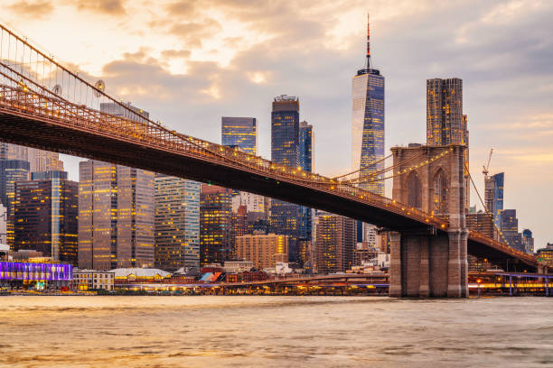 new york city skyline at sunset with brooklyn bridge and lower manhattan - estado de nova york imagens e fotografias de stock