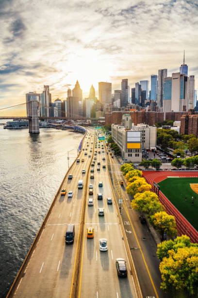 vue surélevée de new york au coucher du soleil depuis le pont de manhattan - east river drive photos et images de collection