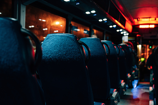 Interior view of a bus at night. View from back seat in a coach bus. Selective focus.