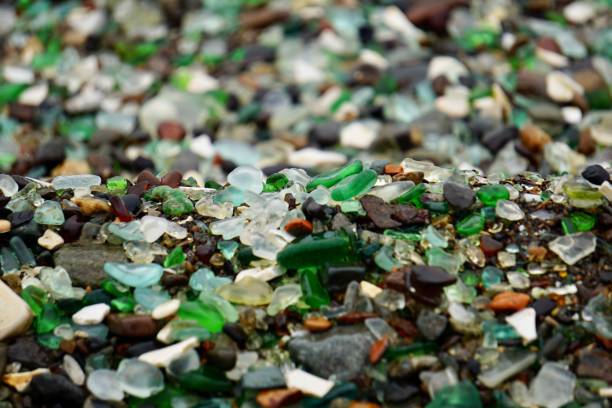 glass is a bay on the northern shore of peter the great bay of the sea of japan. it is part of the ussuri bay. a wave rolls over a multicolored glass beach.s - broken glass green shattered glass imagens e fotografias de stock