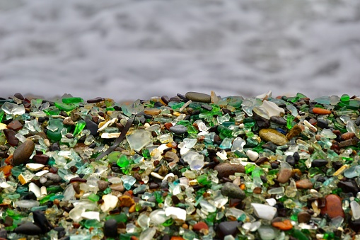 A piece of glass in the form of a heart on the beach. Multicolored glass on the beach. Wet multicolored glass on the beach of Vladivostok.