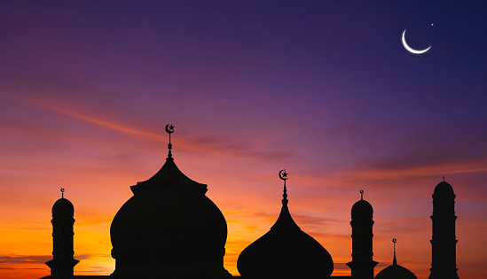Silhouette of Mosques Dome on colorful twilight and Crescent Moon on dusk sky background, symbol islamic religion Ramadan and free space for text arabic, Eid al-Adha, Eid al-fitr, Mubarak