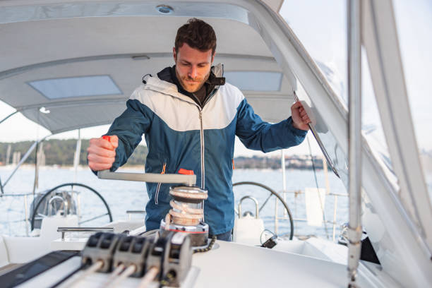 istock Young Sailor Winding Rope Manually With Winch On Sailboat 1451761804