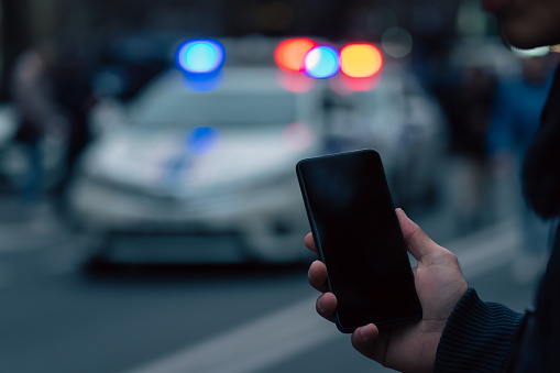 Holding a phone against the backdrop of police cars in the city