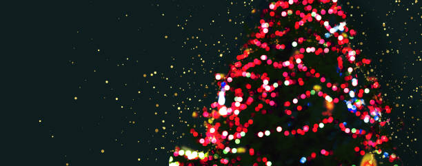 istock Blurred Christmas tree, gifts and red festive bokeh lighting on a black background. Blurred holiday background. 1451775685