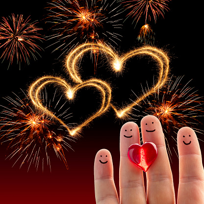 Happy finger people with a red heart. Fireworks and two hearts made of sparkler trace on the background.