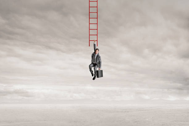 istock Man Hanging From Bottom Rung Of Ladder 1451785275