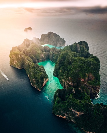 An aerial view of a forested green rocky island with a sandy beach in Thailand, Krabi, Phi Phi Island, Maya bay