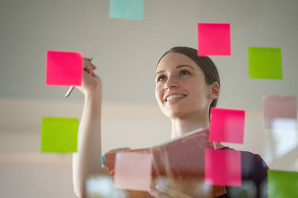 istock Confident businesswoman planning while looking at adhesive notes stuck on a glass wall. 1451786532
