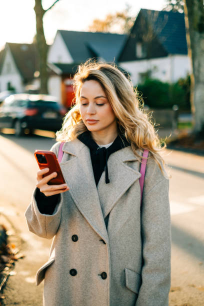istock Young caucasian woman using mobile phone while walking on a city street. 1451788322