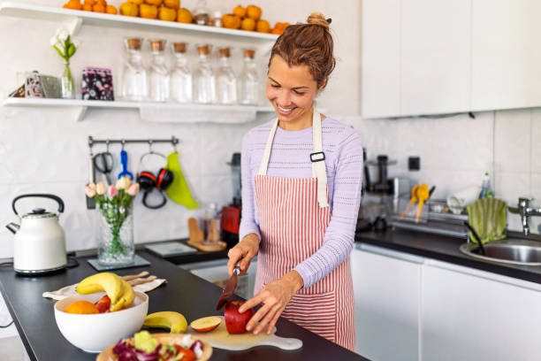 istock Young woman in the kitchen preparing a fruit salad slicing an apple 1451788616