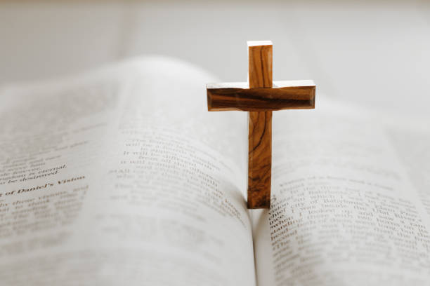 istock Wooden cross standing on open holy bible 1451792937