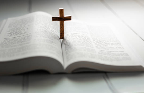 istock Wooden cross standing on open holy bible 1451792969