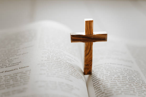 istock Wooden cross standing on open holy bible 1451792975