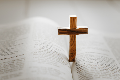 Silhouette christian hand rising over blurred cross on spiritual light background