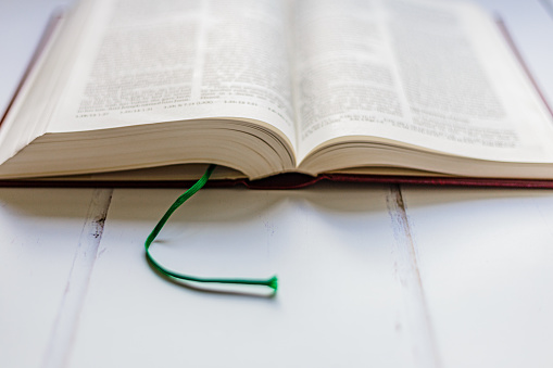 An open holy bible on a white wooden surface.