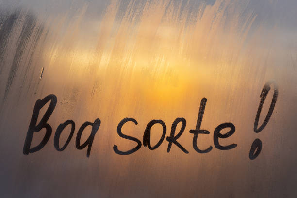 lettering testo spagnolo boa sorte buona fortuna in inglese messaggio scritto dito sul vetro nebbioso finestra bagnata del tramonto - sorte foto e immagini stock