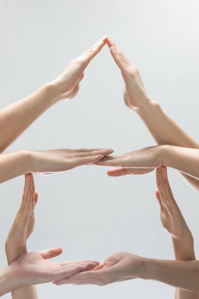istock Vertical shot of helping hands making a pyramid in front of a gray background 1451802089