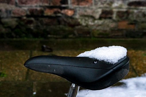 Cambridge public street in the snow with a bicycle against railings in the foreground.