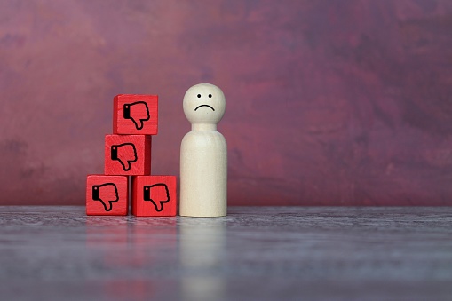 Sad wooden doll and thumbs down icon. Rejection, refusal, turn down and decline concept