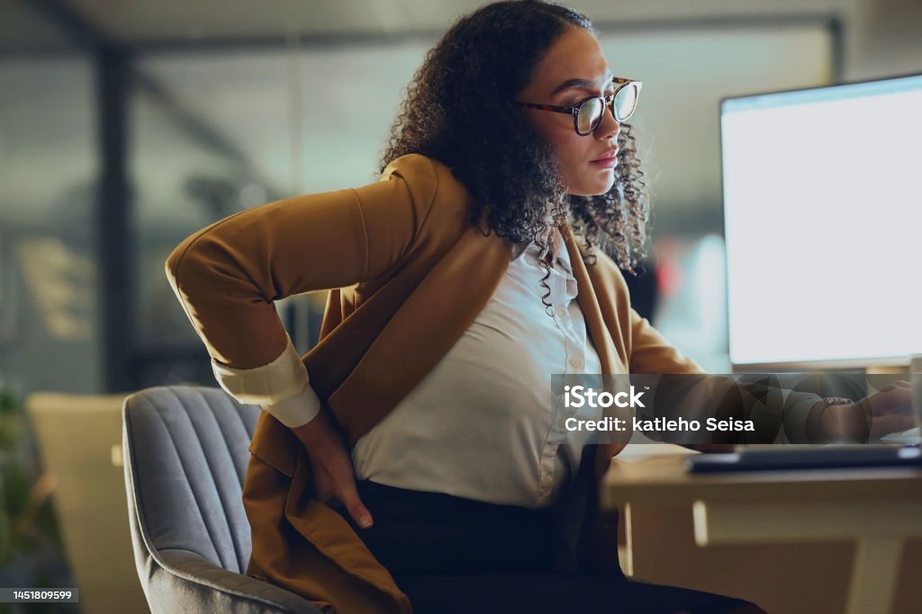 Backache, business woman and computer research at night in office with burnout, stress and spine, discomfort and mockup. Back pain, black woman and posture problem while working late on deadline One Woman Only Stock Photo