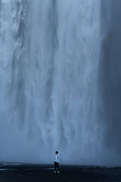 istock Man standing at base of Skogafoss Waterfall, Iceland 1451811175