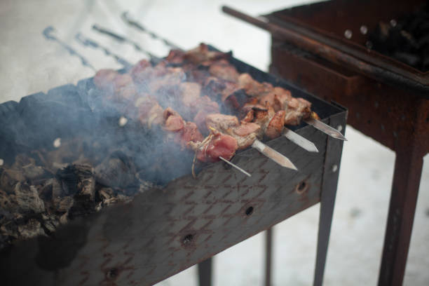 istock Frying meat on fire. Meat strung on blade. Outdoor kitchen. 1451815612