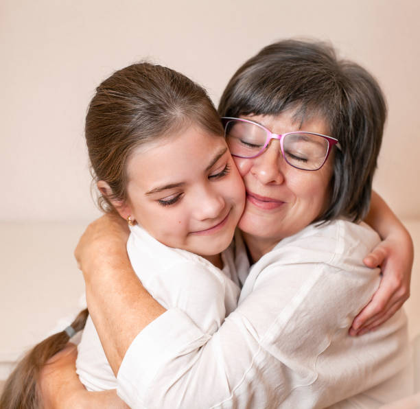 istock grandmother hugging granddaughter in home interior 1451815783