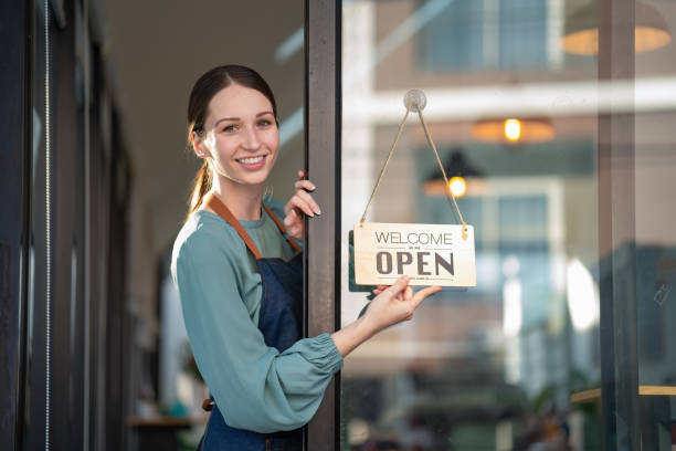 istock A beautiful young coffee shop owner holds an open sign. 1451820905