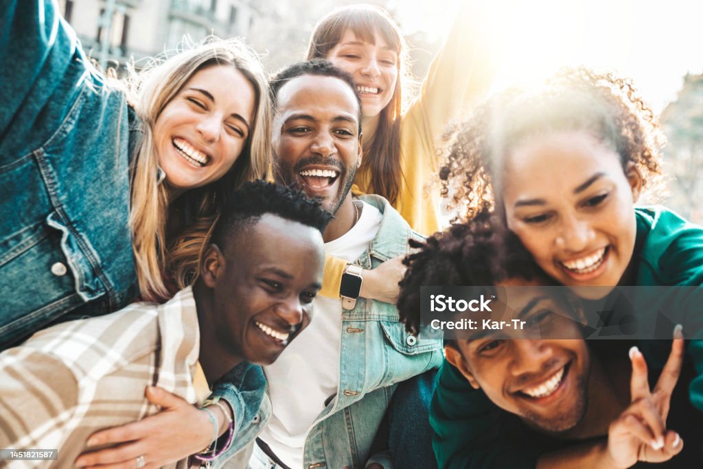 Happy multiracial friends having fun hanging out on city street - Group of young people laughing out loud together outside - Friendship concept with guys and girls enjoying weekend Generation Z Stock Photo