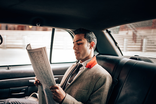 business man reading a newspaper on the taxi