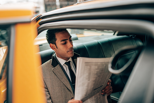 business man reading a newspaper on the taxi