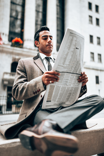 Standing businessman reading the newspaper