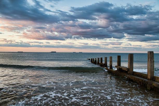 istock Cloudy sky over calm sea with breakwaters, Isle of Wight, England 1451829954