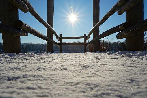 Detail from a Dock also pier with white snow leads to the sun. Blue sky. Deep perspective. Nobody. Copy space. Winter in Germany.