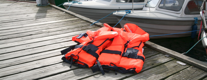 Red Life Jackets on pier with boats in background