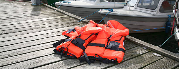 Life Jacket on deck Red Life Jackets on pier with boats in background life jackets stock pictures, royalty-free photos & images