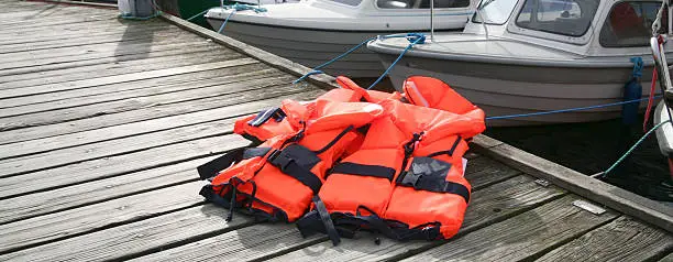 Red Life Jackets on pier with boats in background